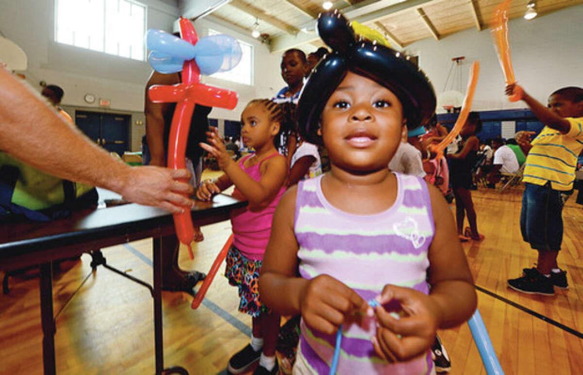 Clockwise, Zariah Smith gets a balloon hat from Magical Memories during the Roodner Court Family Day Saturday at Nathaniel Ely School. Redly Wolfe and Ramonce Charles gets free back packs from the New Beginnings Church. Tamariah Peterson, 4, gets her face painted.