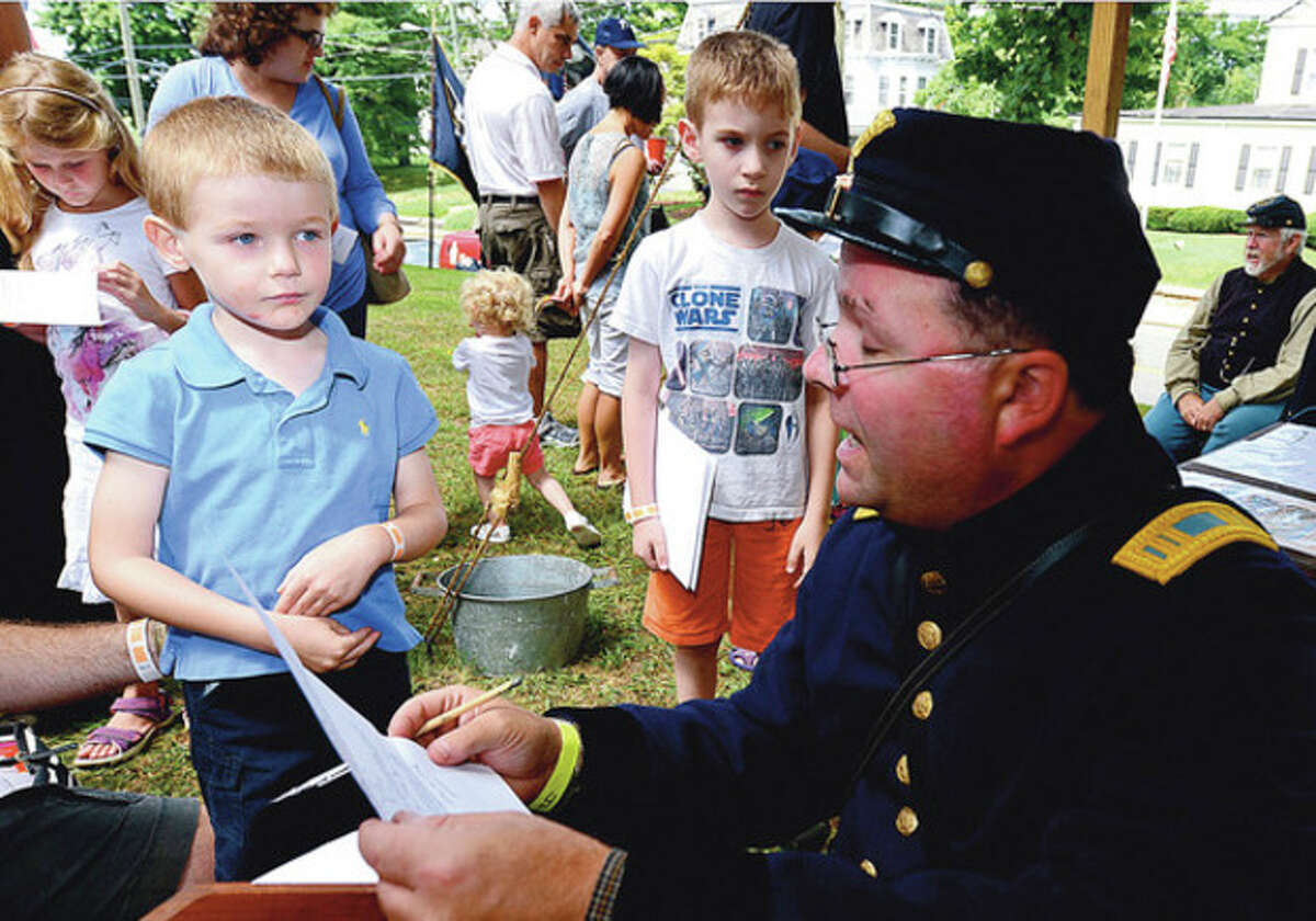 Hour photos / Erik Trautmann Above, Tristan Meyer-Mitchell, 4, enlists into the union army during the Norwalk Historical Society's Civil War BBQ at Mill Hill Historic Park Saturday. Below, Civil War re-enactor Ralph Lim takes a break and enjoys a pulled pork sandwich.