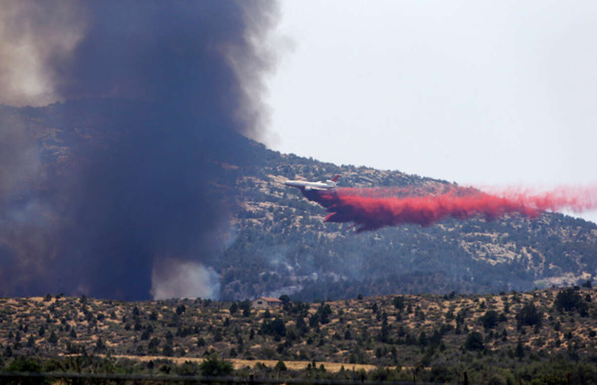 An aerial tanker drops fire retardant on a wildfires threatening homes near Yarnell, Ariz., Monday, July 1, 2013. An elite crew of firefighters was overtaken by the out-of-control blaze on Sunday, killing 19 members as they tried to protect themselves from the flames under fire-resistant shields. (AP Photo/Chris Carlson)