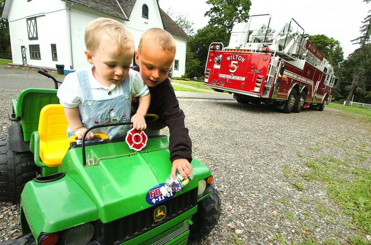 Hour Photo/ Alex von Kleydorff. l-R Grandson Dalton Dolnier and Cole Johnson play in a smaller version of a fire truck at the retirement party for Karl Dolnier on Sunday.