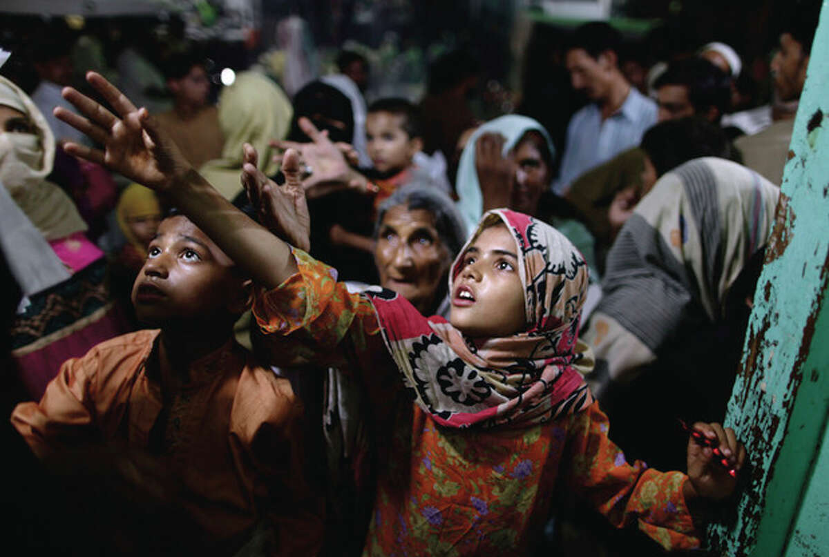 Pakistani women and children reach for donated food during the last Friday of the Muslim holy fasting month of Ramadan, at a restaurant in Rawalpindi, Pakistan, Friday, Aug. 17, 2012. For many years, Pakistan required all Sunni Muslims, who make up a majority of the country's population, to pay zakat to the government. That regulation changed recently, but many Pakistanis seem unaware and continue to pull their money out of the bank to elude the state. The food is donated by wealthy local Muslims who give money to local vendors to feed the poor during Islam's holiest month. (AP Photo/Muhammed Muheisen)