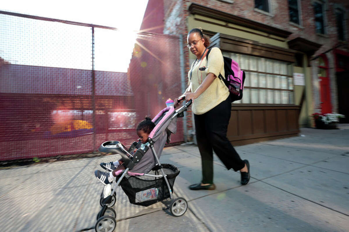 Ke'sha Scrivner, right, heads to a subway Metro stop after picking up her daughter Ka'Lani Scrivner, 1, from day care, Tuesday, July 9, 2013, in Washington. Once on welfare, Scrivner worked her way off by studying early childhood education and landing a full-time job for the District of Columbia?’s education superintendent. She sees education as the path to a better life for herself and all five of her children, pushing them to finish high school and continue with college or a trade school. (AP Photo/Alex Brandon)
