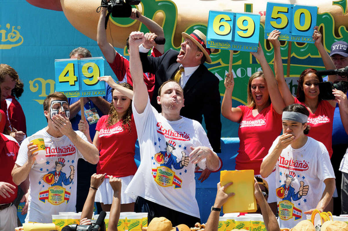 Joey Chestnut, center, wins the Nathan's Famous Fourth of July International Hot Dog Eating contest with a total of 69 hot dogs and buns, alongside Tim Janus, left, and Matt Stonie, right, Thursday, July 4, 2013 at Coney Island, in the Brooklyn borough of New York. (AP Photo/John Minchillo)