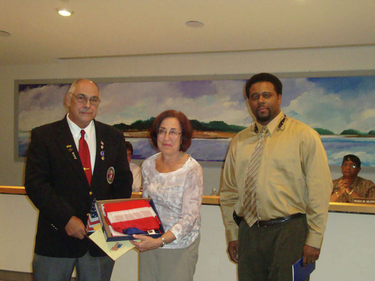Dr. Susan Marks holds the American flag presented to her by Norwalk Veterans Memorial Committee Chairman Dan Caporale (left) and Jarvin Johnson, veterans affairs specialist for Congressman Jim Himes, D-4.