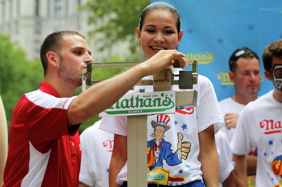Sonya Thomas smiles as she stands on the scale during the official weigh-in for the Nathan's Fourth of July hot dog eating contest, Wednesday, July 3, 2013 at City Hall park in New York. (AP Photo/Mary Altaffer)