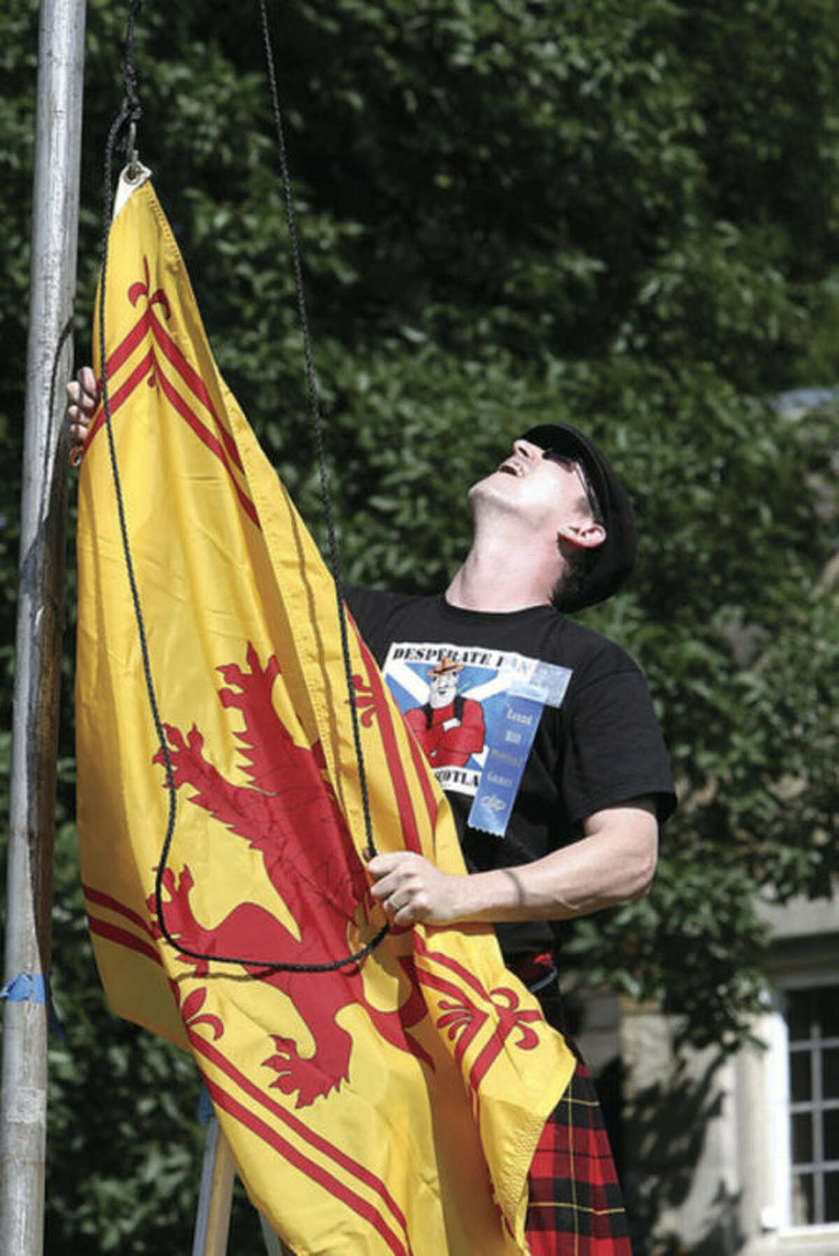 Hour photo / David Esposito Bruce Kennedy of Stamford raises the Flag of Scotland which features the "Lion Rampant" at the 84th annual Round Hill Highland Games Saturday at Cranbury Park.