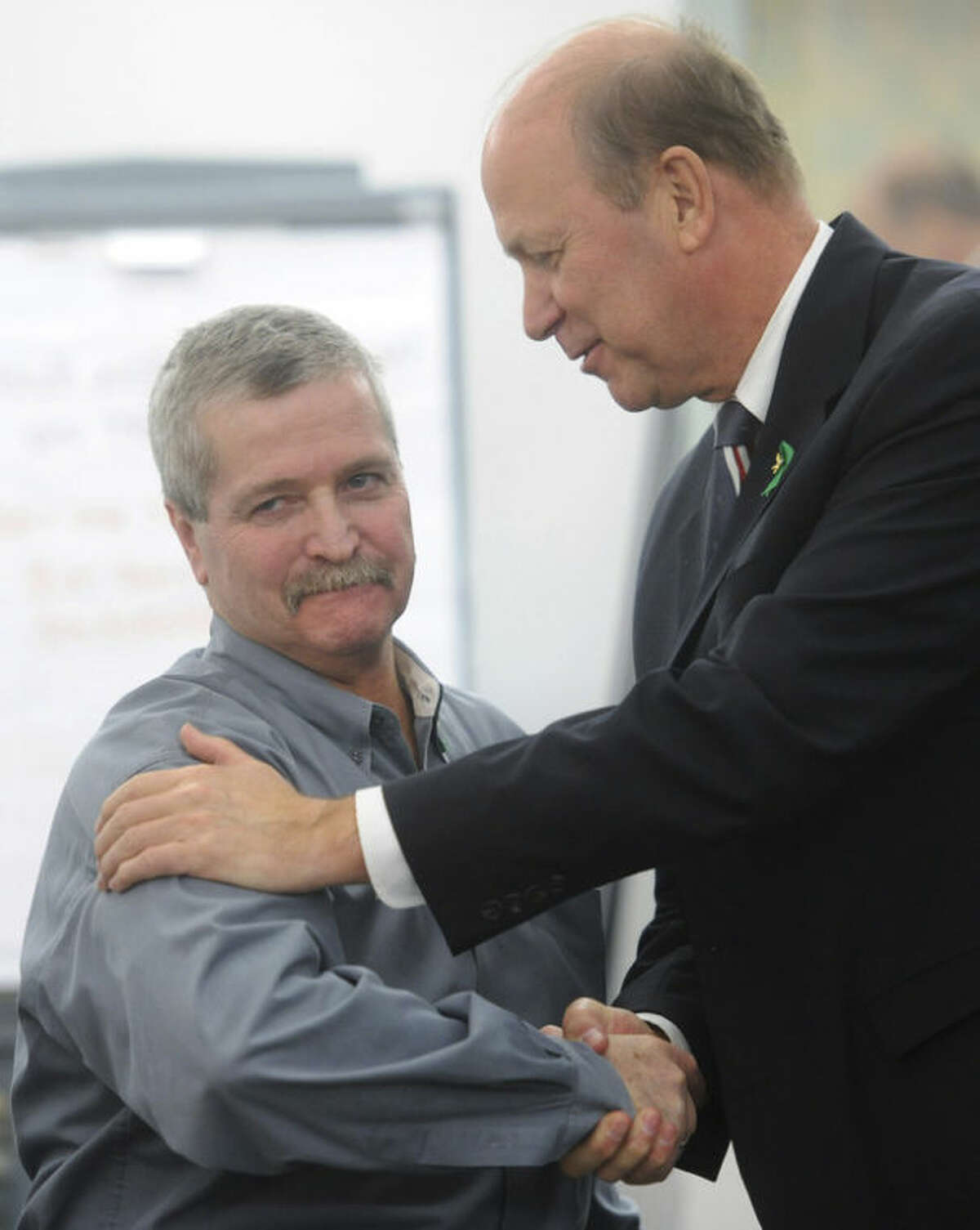 In this April 17, 2013 photo, Robert Nute, left, is congratulated by Newtown Police Chief Michael Kehoe after winning an emergency telecommunications award, at the Newtown Municipal Center in Newtown, Conn. Nute, of the Newtown Emergency Communications Center, handled dispatch calls during the Sandy Hook Elementary School shooting on Dec. 14, 2012. The dispatchers at the Newtown center have won praise from officials and colleagues around the country for their role in the response to the shooting. The call center director said the staff has been lifted by the outpouring of support as the dispatchers recover emotionally, along with the community that still peppers them with calls over anything out of the ordinary. (AP Photo/The News-Times, Tyler Sizemore) MANDATORY CREDIT