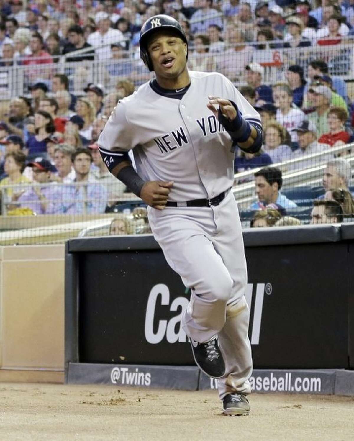 New York Yankees' Robinson Cano races to the dugout after scoring the go-ahead run on a sacrifice fly by Lyle Overbay off Minnesota Twins pitcher Caleb Thielbar in the sixth inning of a baseball game on Wednesday, July 3, 2013, in Minneapolis. (AP Photo/Jim Mone)