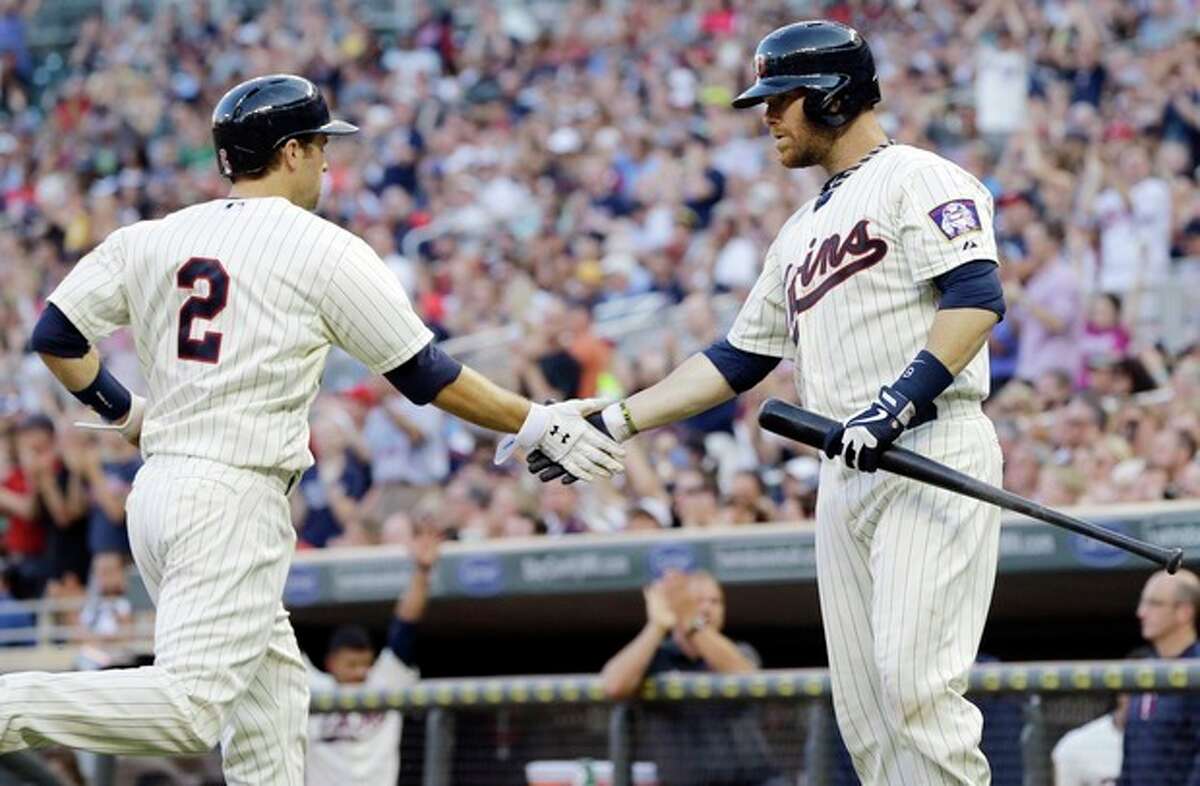 Minnesota Twins' Ryan Doumit, right, congratulates teammate Brian Dozier who scores on an RBI-double by Joe Mauer off New York Yankees pitcher CC Sabathia in the third inning of a baseball game on Wednesday, July 3, 2013, in Minneapolis. (AP Photo/Jim Mone)
