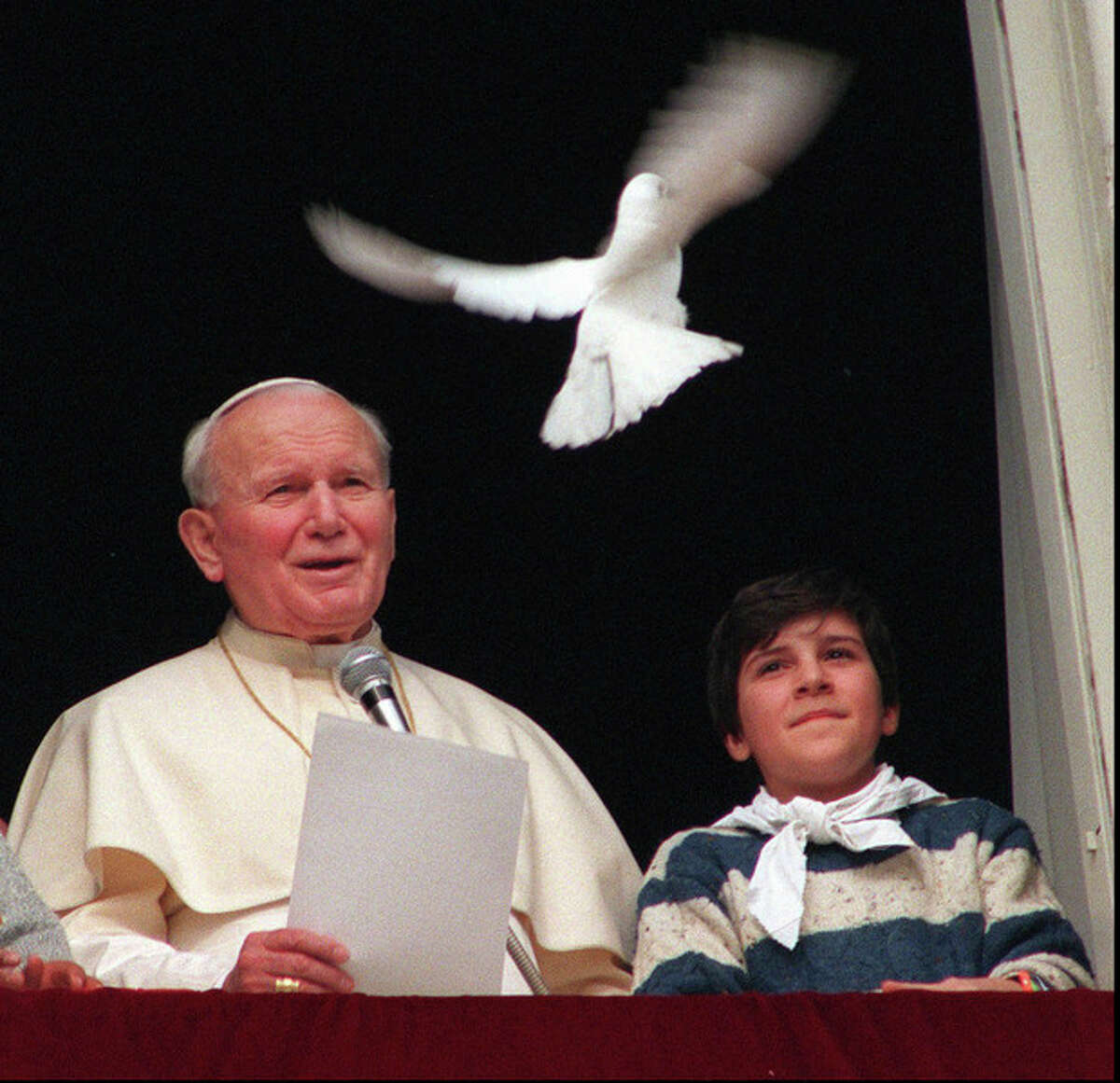 FILE - In this Jan. 28 1996 file photo, Pope John Paul II looks at a dove after he delivered the noon blessing from the window of his studio overlooking St. Peter's square at the Vatican. Pope Francis has cleared John Paul II for sainthood, approving a miracle attributed to his intercession. Francis also decided Friday, July 5, 2013, to canonize another beloved pope, John XXIII, even though there has been no second miracle attributed to his intercession. The Vatican said Francis approved a decision by cardinals and bishops. The ceremonies are expected before the end of the year. (AP Photo/Bruno Mosconi, File)