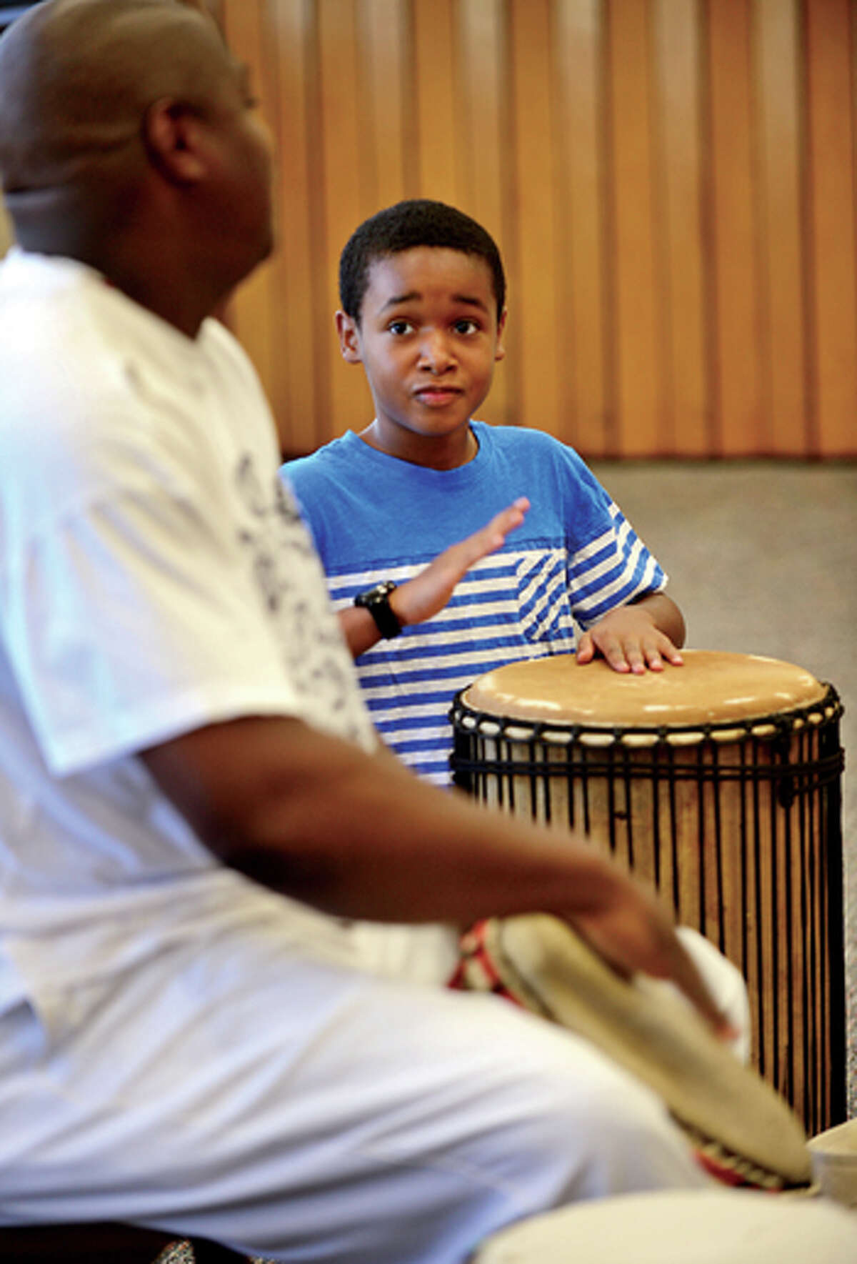 Christian Tapper, 10, drums along with Henry Jones of the Infinite Roots drum troupe at the Norwalk Public Library Friday. Hour photo / Erik Trautmann