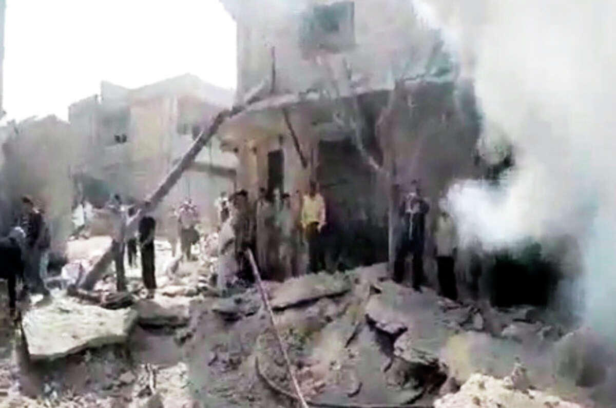 In this image made from amateur video released by the Shaam News Network and accessed Tuesday, Aug. 28, 2012, Syrian men stand in the rubble of a destroyed building from purported airstrikes in Kfarnebel, Idlib province, northern Syria. (AP Photo/Shaam News Network via AP video) THE ASSOCIATED PRESS IS UNABLE TO INDEPENDENTLY VERIFY THE AUTHENTICITY, CONTENT, LOCATION OR DATE OF THIS HANDOUT PHOTO