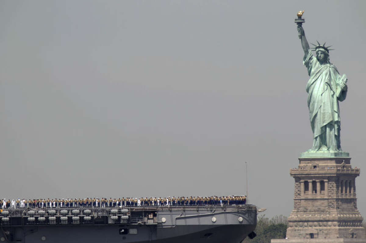FILE - In this May 25, 2011 file photo, sailors stand on deck of the USS Iwo Jima as it passes Liberty Island and the Statue of Liberty during Fleet Week in New York. After hundreds of National Park Service workers from as far away as California and Alaska spent weeks cleaning and making repairs on the national landmark in the wake of Superstorm Sandy, Liberty Island is scheduled to reopen to the public on Independence Day, July 4, 2013. (AP Photo/Seth Wenig, File)