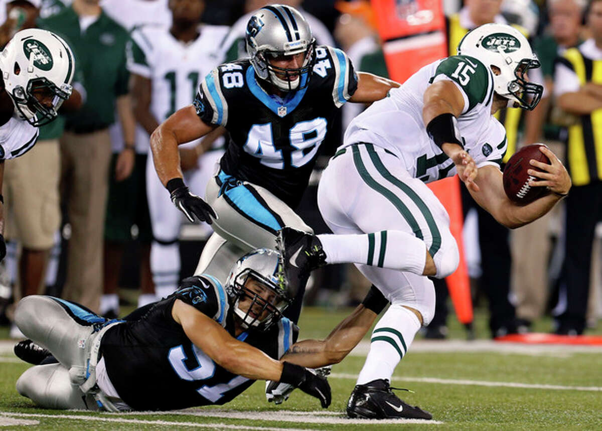 New York Jets quarterback Tim Tebow (15) avoids tackles from Carolina Panthers' Jordan Senn (57) and J.J. Finley (49) during the second half of a preseason NFL football game Sunday, Aug. 26, 2012, in East Rutherford, N.J. (AP Photo/Julio Cortez)