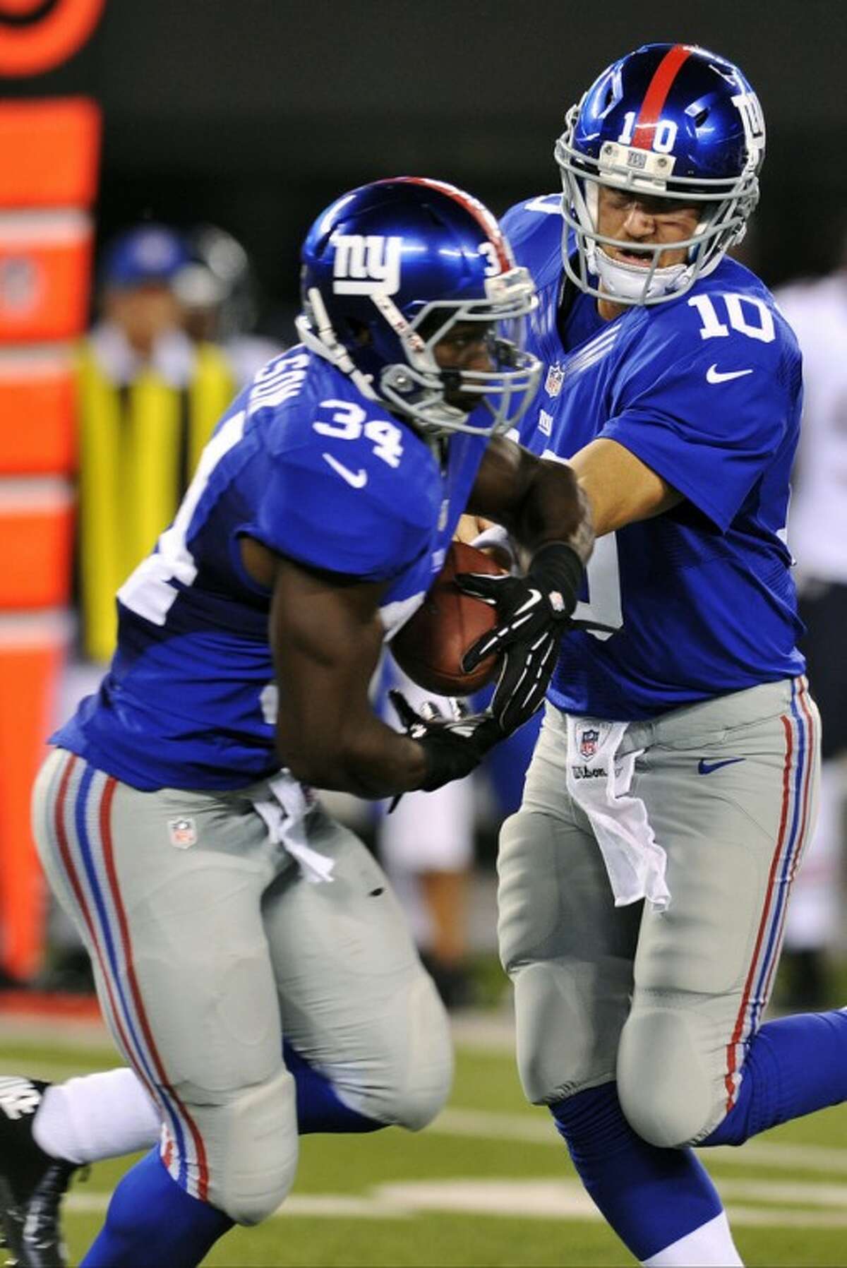 FILE - In this Aug. 24, 2012, file photo, New York Giants quarterback Eli Manning (10) hands the ball to running back David Wilson (34) during the first half of an NFL preseason football game against the Chicago Bears in East Rutherford, N.J. The running game, which was the worst in the NFL in 2011, has a chance to run over people if first-round draft choice Wilson lives up to the hype. The Giants are scheduled to begin their season on Sept. 5 at home against the Dallas Cowboys. (AP Photo/Bill Kostroun, File)