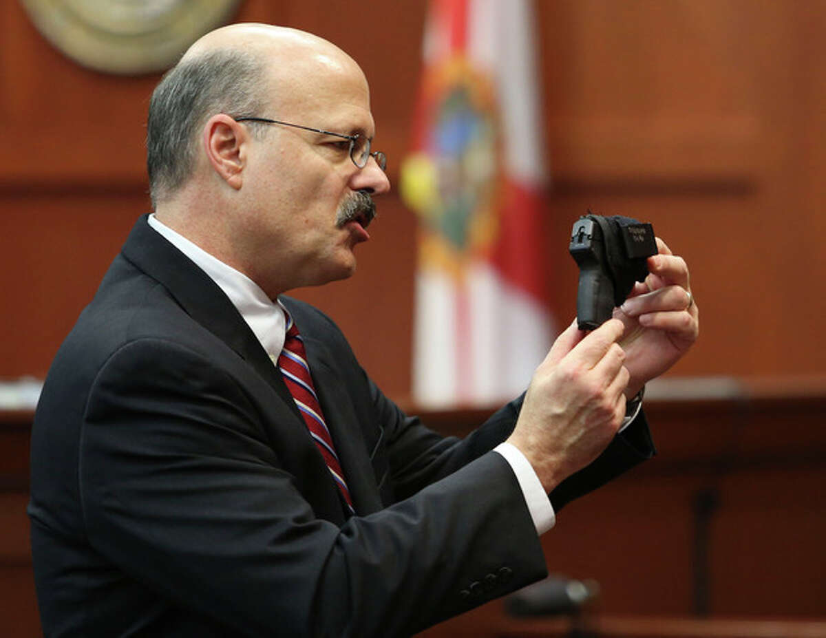 Assistant state attorney Bernie de la Rionda shows George Zimmerman's gun to the jury while presenting the state's closing arguments against Zimmerman during his trial in Seminole circuit court in Sanford, Fla. Thursday, July 11, 2013. Zimmerman has been charged with second-degree murder for the 2012 shooting death of Trayvon Martin. (AP Photo/Orlando Sentinel, Gary W. Green, Pool)