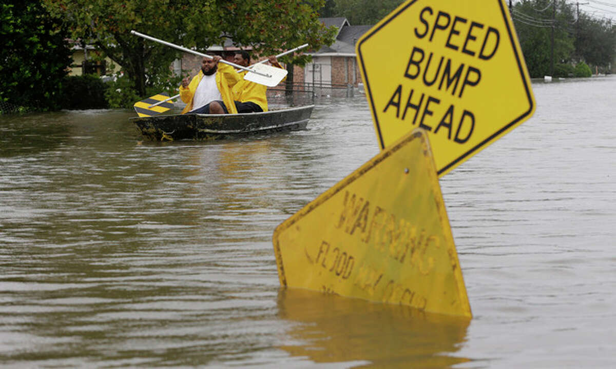 Isaac Fields, left, and Victor Jones use street signs to paddle a boat out of their flooded neighbor, Thursday, Aug. 30, 2012, in LaPlace, La. Isaac has caused major flooding in the region. (AP Photo/Eric Gay)