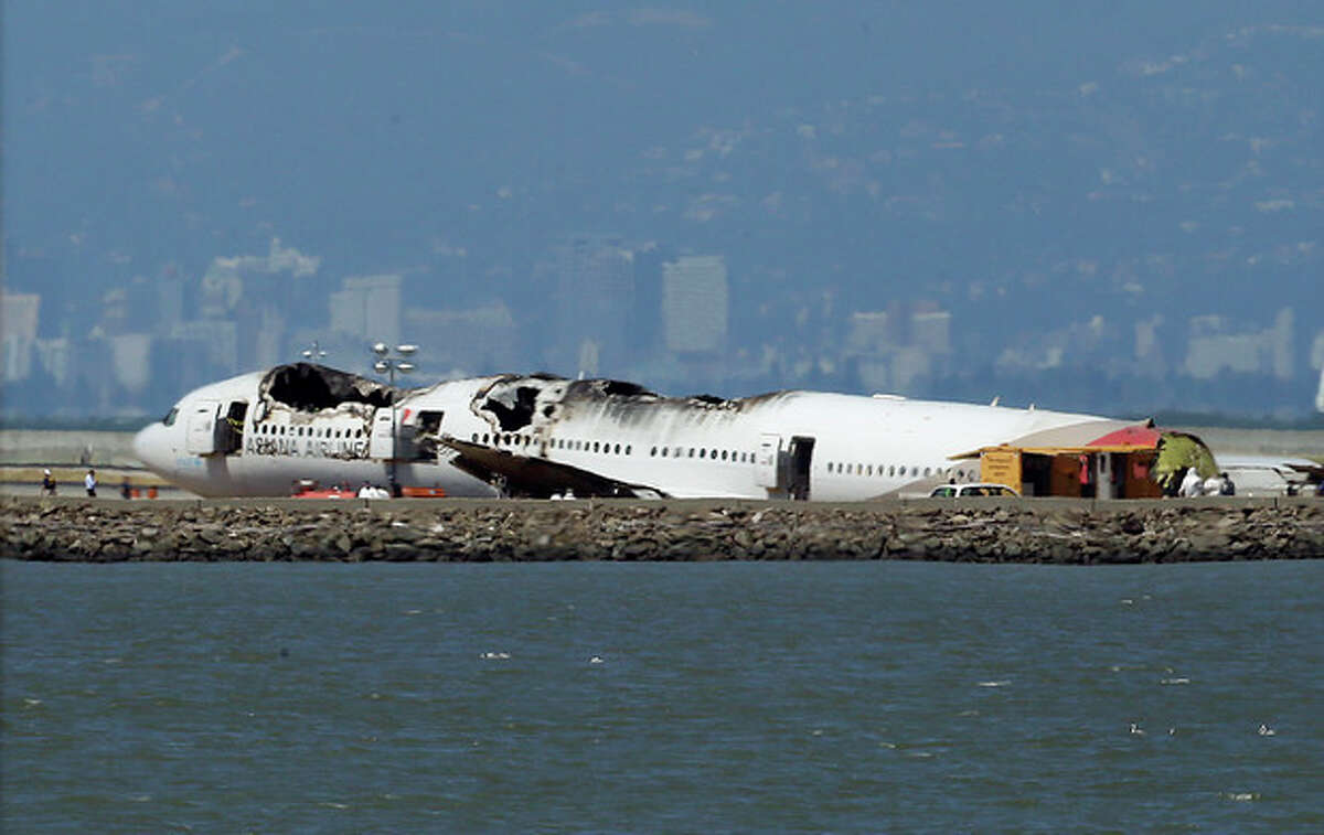 The wreckage of Asiana Airlines Flight 214 that crashed upon landing Saturday at San Francisco International Airport sits on the tarmac Monday, July 8, 2013 in San Francisco. Investigators said the Boeing 777 was traveling "significantly below" the target speed during its approach and that the crew tried to abort the landing just before it smashed onto the runway on Saturday, July 6. Two of the 307 passengers aboard were killed. (AP Photo/Jeff Chiu)