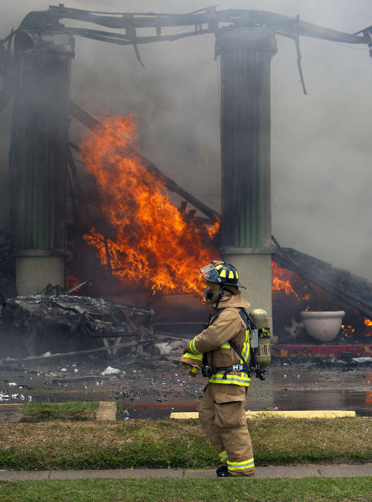 A firefighter stands near a fire at the Southwest Inn, Friday, May 31, 2013, in Houston. A fire that engulfed a Houston motel has injured at least six firefighters, including two critically, and three people are missing. (AP Photo/Houston Chronicle, Cody Duty) MANDATORY CREDIT