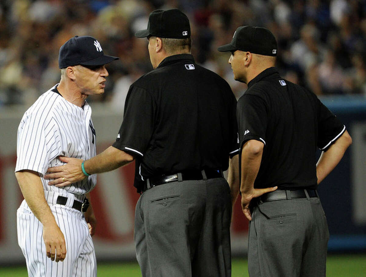 New York Yankees manager Joe Girardi, left, is restrained by first base umpire Gary Cederstrom after Girardi was ejected by second base umpire Vic Carapazza, right, during the fifth inning of a baseball game against the Boston Red Sox, Friday, May 31, 2013, at Yankee Stadium in New York. (AP Photo/Bill Kostroun)