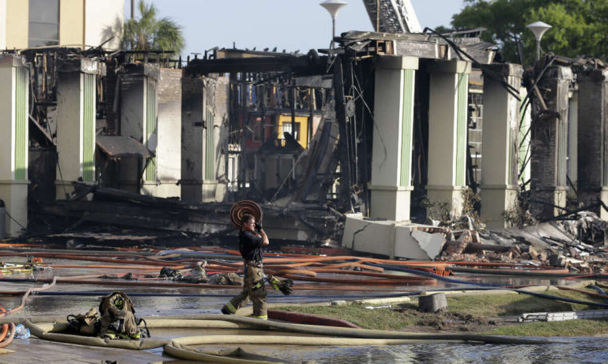 A Houston firefighter carries a firehose from the scene where four firefighters were killed while battling a fire that engulfed a motel and restaurant on Friday, May 31, 2013, in Houston. At least five other people were hospitalized, authorities said. (AP Photo/David J. Phillip)