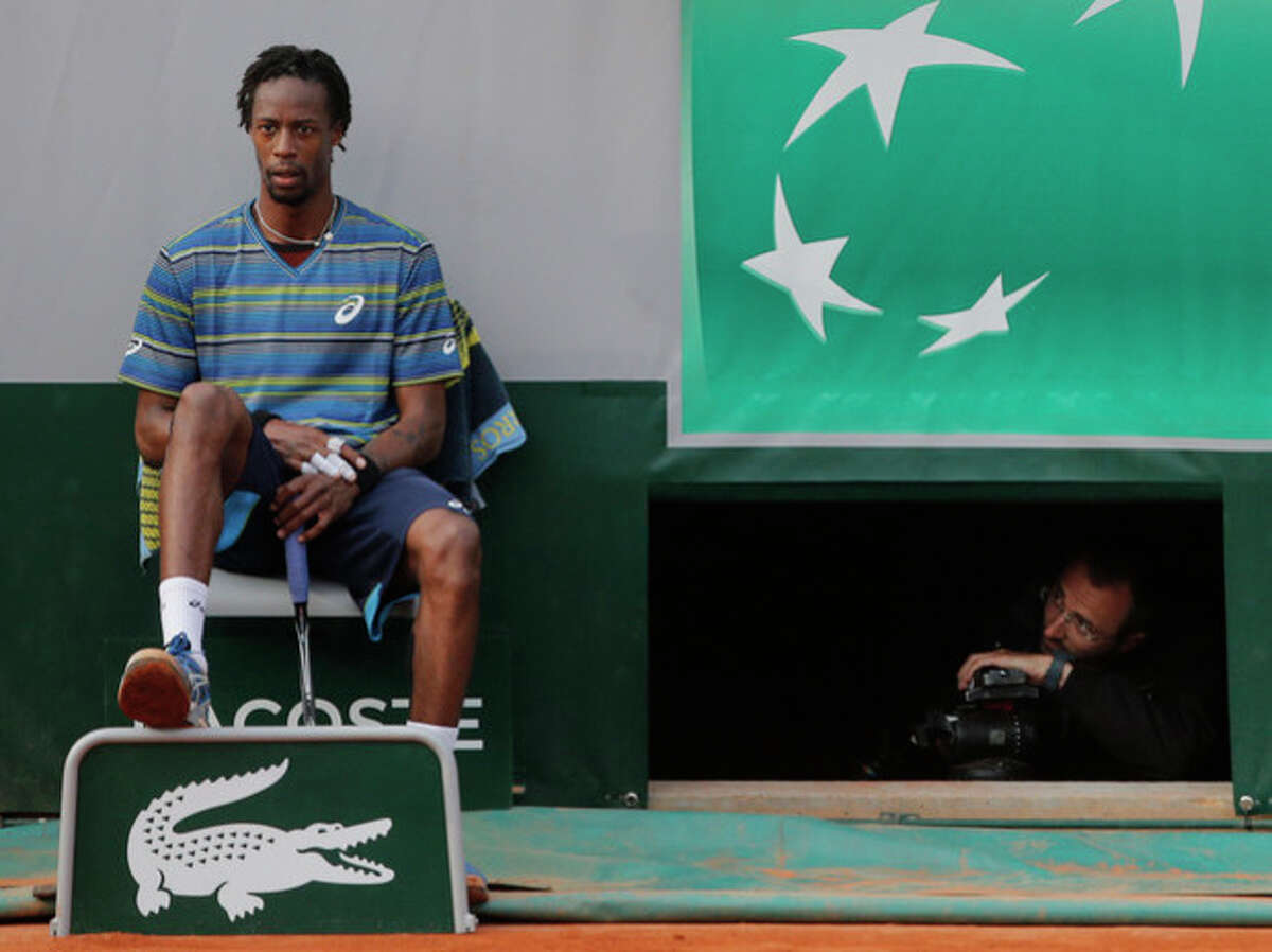 A man looks at Gael Monfils of France, left, as he rest on the seat of a lines man in his third round match against Tommy Robredo of Spain at the French Open tennis tournament, at Roland Garros stadium in Paris, Friday, May 31, 2013. Robredo won in five sets 2-6, 6-7, 6-2, 7-6, 6-2. (AP Photo/Michel Spingler)