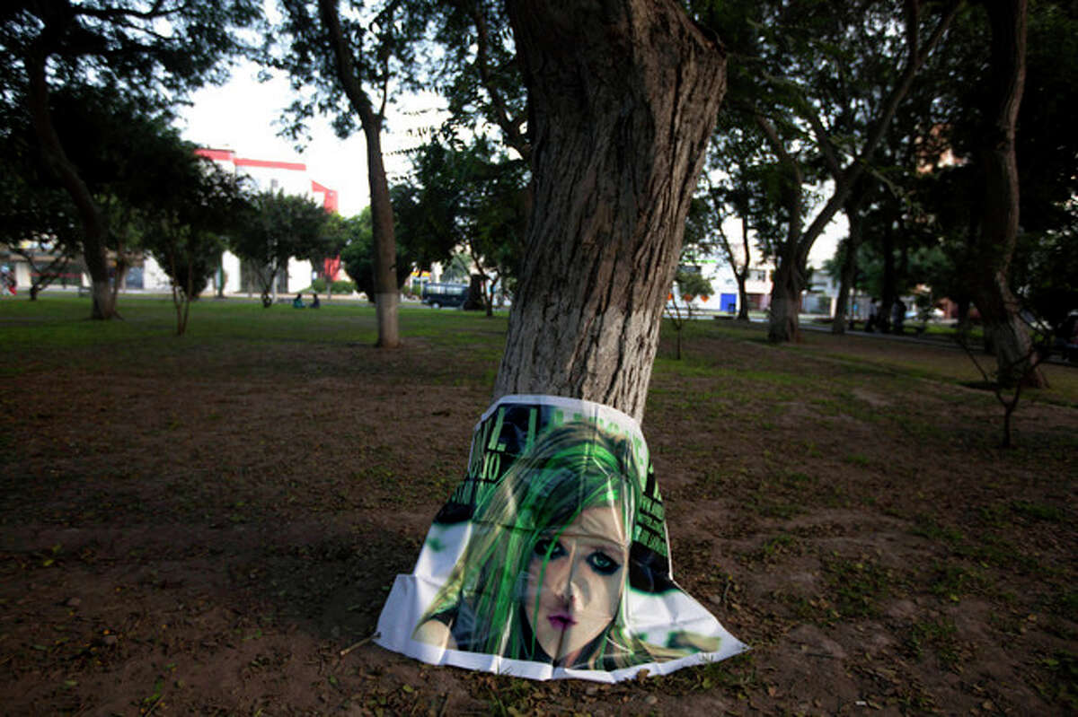 In this May 11, 2013 photo, a poster of South Korean K-pop singer Woorissica stands against a tree trunk after it was left behind by fans who gathered here in Ramon Castilla park in Lima, Peru. Teenagers throughout Latin America have long looked north for pop music inspiration. Now the East is rising, with a large and enthusiastic cult of fans in some countries following the K-pop music from Korea. (AP Photo/Martin Mejia)