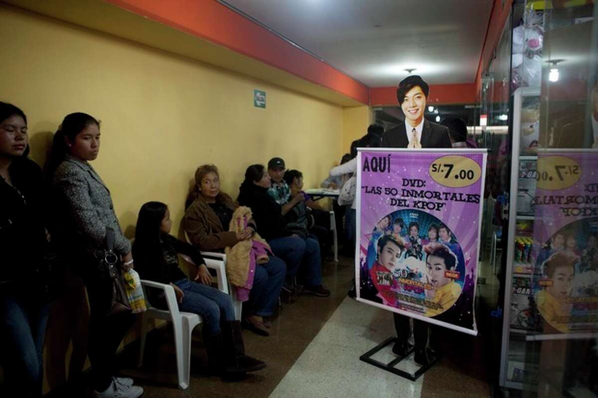 In this May 4, 2013 photo, parents and their children wait for a store to open that sells Korean pop music, known as K-Pop, at the Arenales shopping center in Lima, Peru. Arenales has entire floors dedicated to South Korean music, clothes and food. (AP Photo/Martin Mejia)