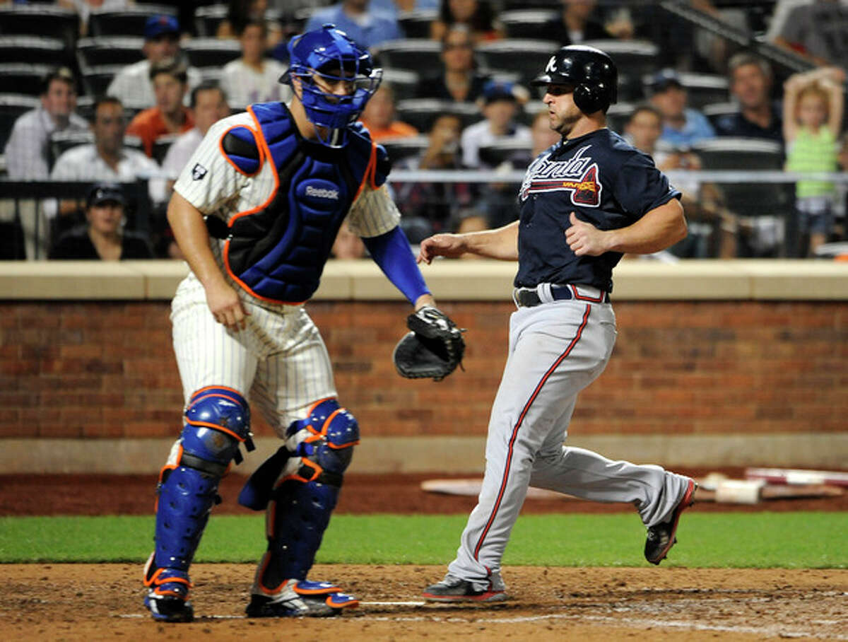 Atlanta Braves' Dan Uggla scores at home plate on a sacrifice fly by David Ross as New York Mets catcher Kelly Shoppach waits for the throw in the seventh inning of a baseball game on Friday, Sept. 7, 2012, at Citi Field in New York. (AP Photo/Kathy Kmonicek)
