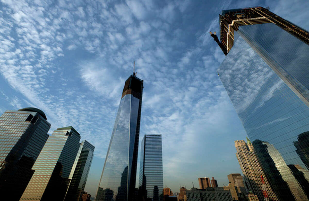 One World Trade Center, center, rises above the National September 11 Memorial and Museum at the World Trade Center, Thursday, Sept. 6, 2012 in New York. Tuesday will mark the eleventh anniversary of the terrorist attacks of Sept. 11, 2001. The World Financial Center is on the left, and Four World Trade Center is at right. (AP Photo/Mark Lennihan)