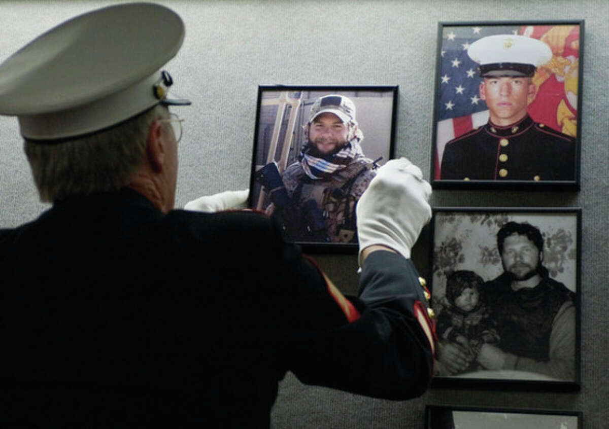 AP photo Ret. Marine Sgt. Don Hauser hangs the photograph of Navy SEAL Chief Petty Officer Brian Bill of Stamford on the Connecticut Wall of Honor.