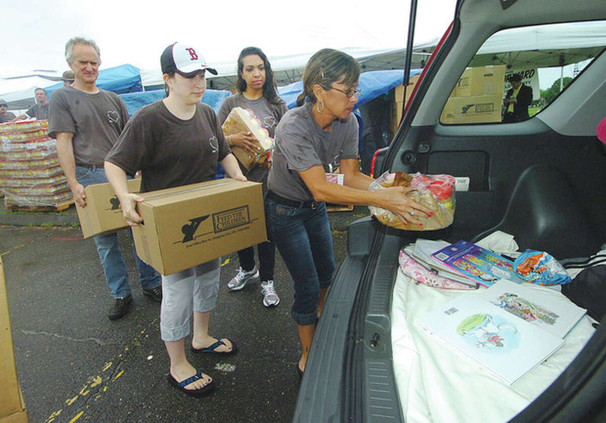 Hour Photo/Alex von Kleydorff . The Salvation Army places jars of Peant Butter and boxes of food on top of coloring books in a families car. The food was distributed to those in need at Veterans park in Norwalk on Monday