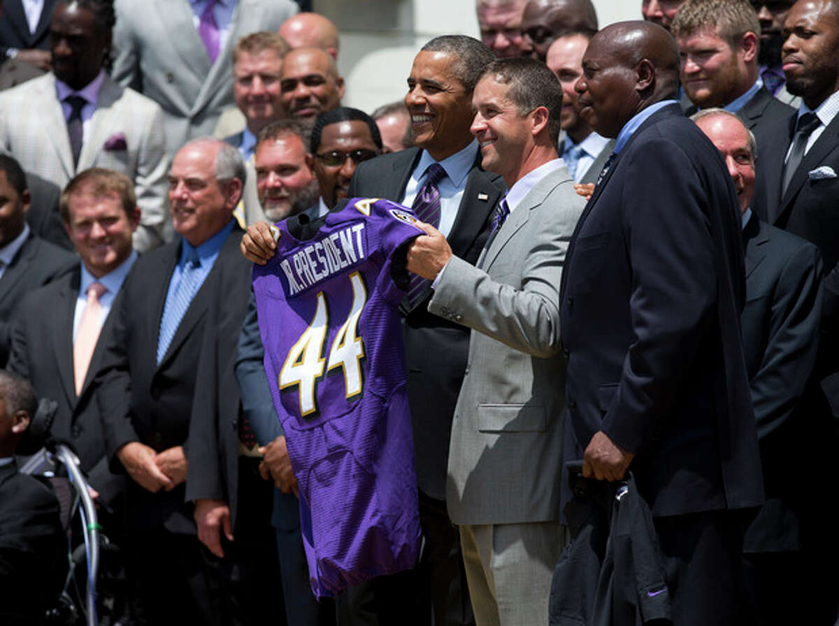 President Barack Obama and Baltimore Ravens head coach John Harbaugh, center, hold a Baltimore Ravens football jersey presented to the president during a ceremony on the South Lawn of the White House in Washington, Wednesday, June 5, 2013, where the president honored the Super Bowl XLVII champs. The Ravens defeated the San Francisco 49ers in Super Bowl XLVII. General Manager Ozzie Newsome is at right. (AP Photo/Evan Vucci)