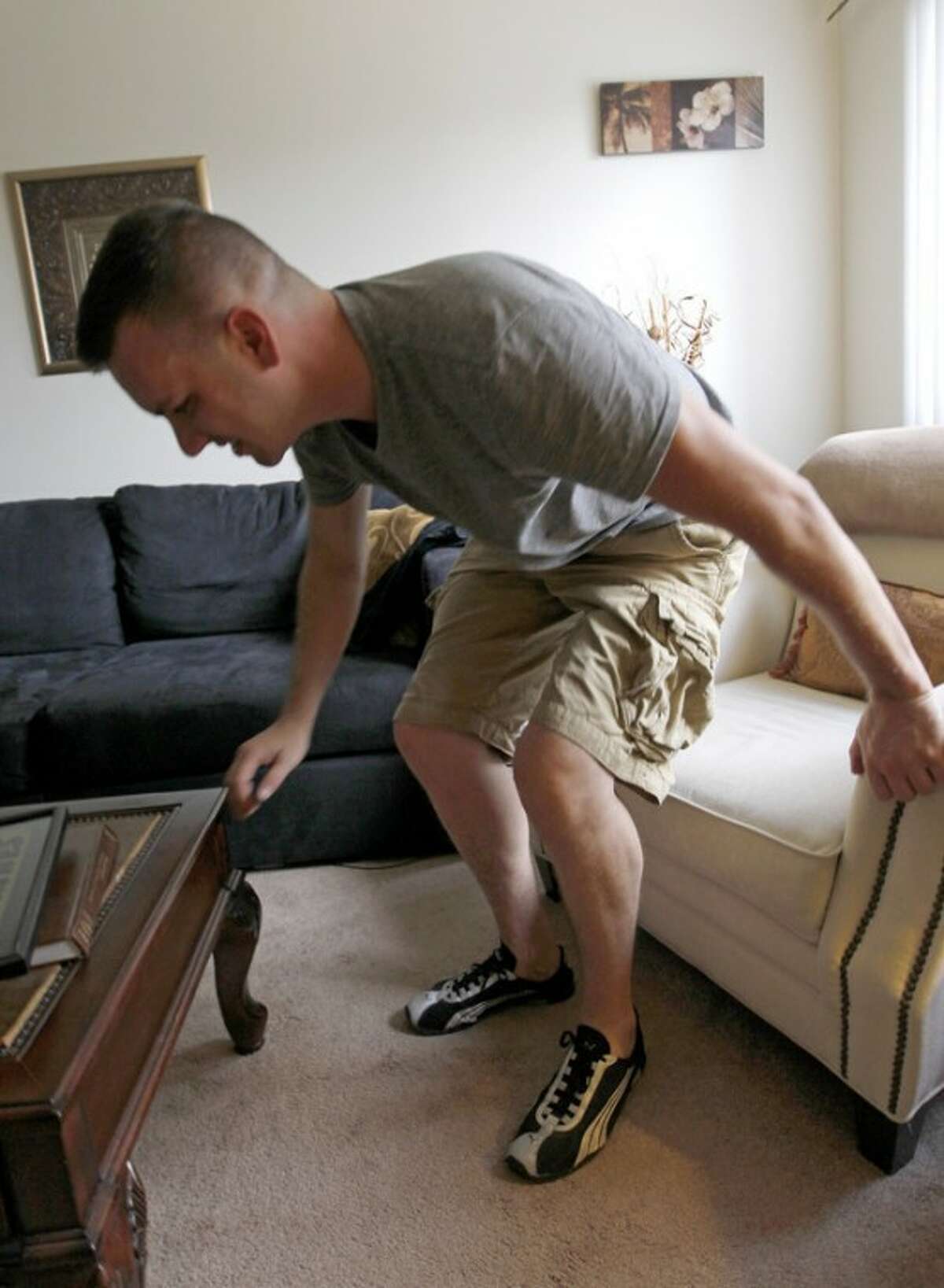 In this Monday, Aug. 20, 2012 photo, Marine Sgt. Ron Strang gets up from a chair in the living room of his home in Jefferson Hills, Pa. just south of Pittsburgh. He lost half of his left thigh muscle in a bomb blast in Afghanistan and with an experimental implant of connective tissue developed from pigs, it has had it strengthened. "It's been a huge improvement," he says. (AP Photo/Keith Srakocic)