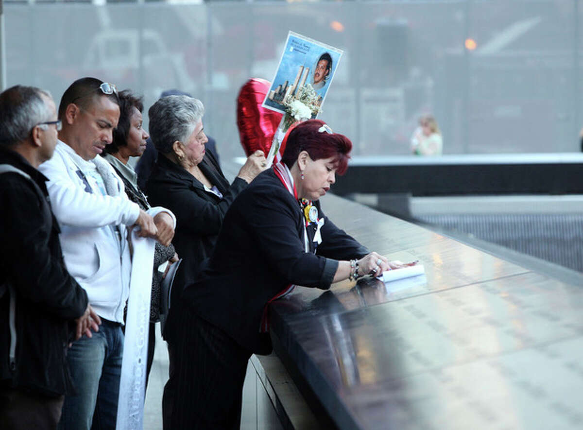 Rosario Tejada, right, of Columbia makes as rubbing of the name of her nephew, Wilder Gomez, of the Queens borough of New York, who died in the north tower of the World Trade Center. She is attending the observances held on the eleventh anniversary of the attacks on the World Trade Center, in New York, Tuesday Sept. 11, 2012. (AP Photo/The Record, Chris Pedota, Pool)
