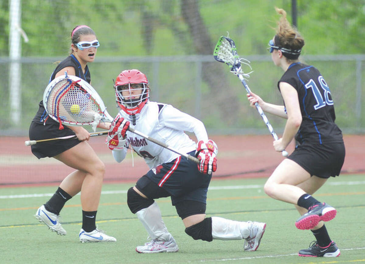 Hour photo/John Nash Brien McMahon girls lacrosse goalie Michele Petrucci reverses direction to avoid two Bunnell Bulldog defenders during Saturday's game in Norwalk.