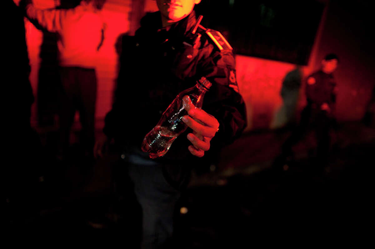 In this Sept. 18, 2012 photo, a state police officer shows a bottle containing a solvent commonly inhaled by addicts, known locally as "mona," that was taken from a person during a routine police patrol in Morelia, Mexico. In cities and towns across Mexico, a nearly six-year offensive against drug cartels has been accompanied by a surge in common crime: assaults and robberies that grab no headlines but make life miserable for ordinary citizens. (AP Photo/Alexandre Meneghini)