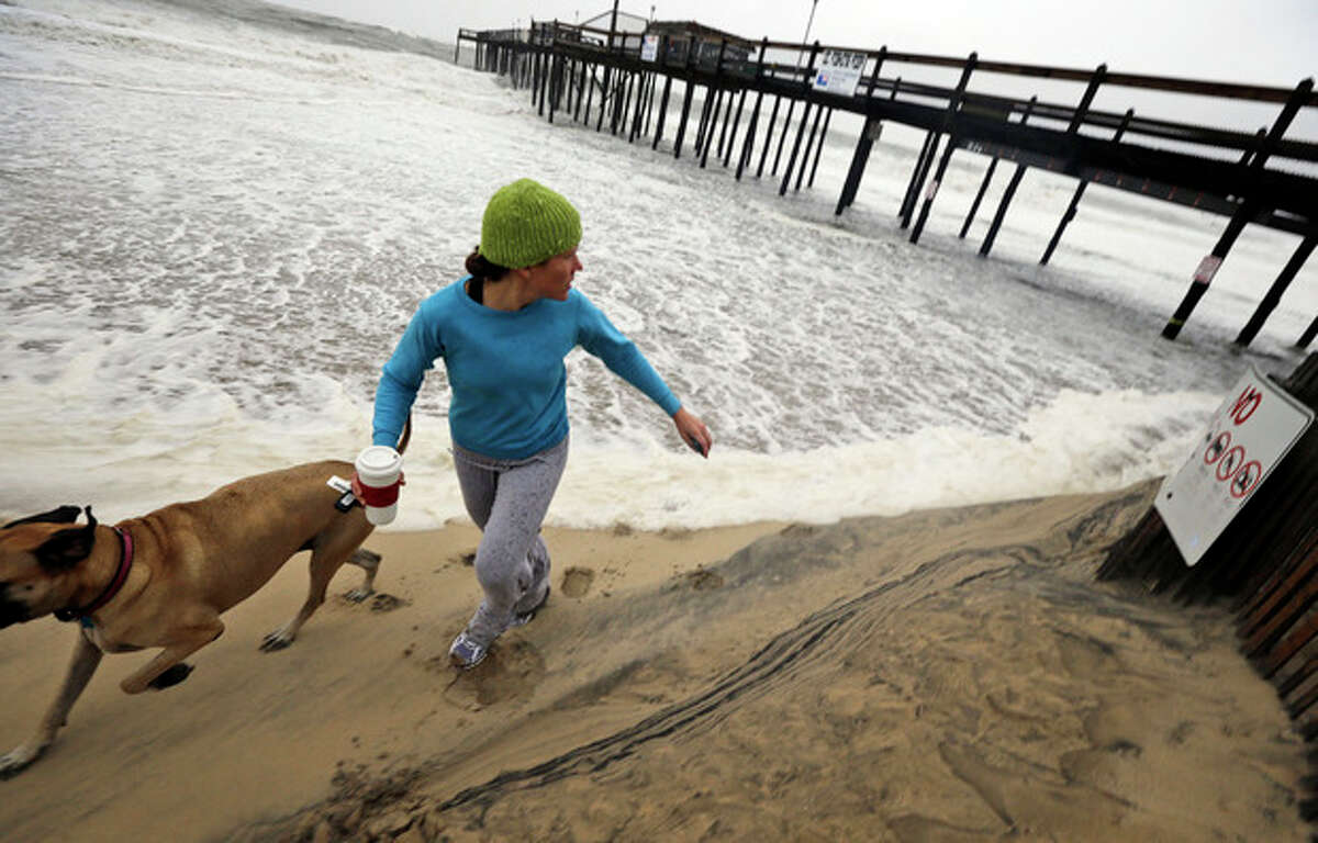Jenny Lind and her dog Greta run away from a wave that comes up the beach as Hurricane Sandy bears down on the East Coast, Sunday, Oct. 28, 2012, in Ocean City, Md. (AP Photo/Alex Brandon)