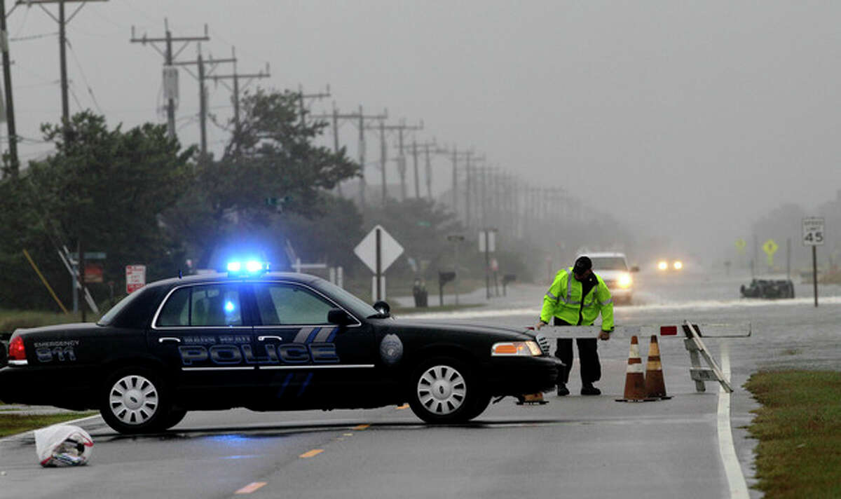 A police officer sets up a road block on South Oregon Inlet Road as water from Hurricane Sandy covers the road in Nags Head, N.C., Sunday, Oct. 28, 2012. (AP Photo/Gerry Broome)