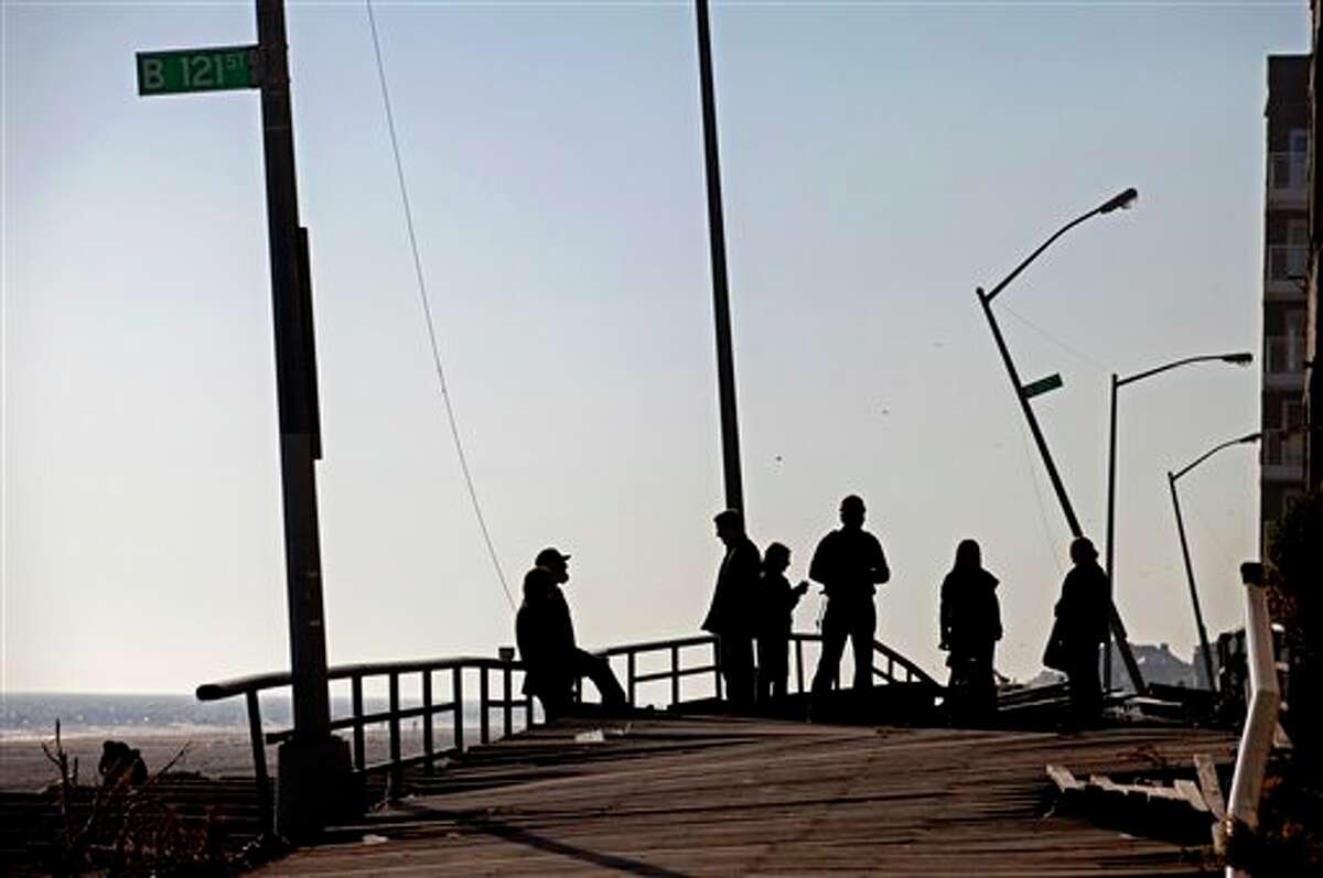 People gather on the buckled boardwalk of the Rockaway Park neighborhood of the borough of Queens, New York, Sunday, Nov. 11, 2012, in the wake of Superstorm Sandy. (AP Photo/Craig Ruttle)
