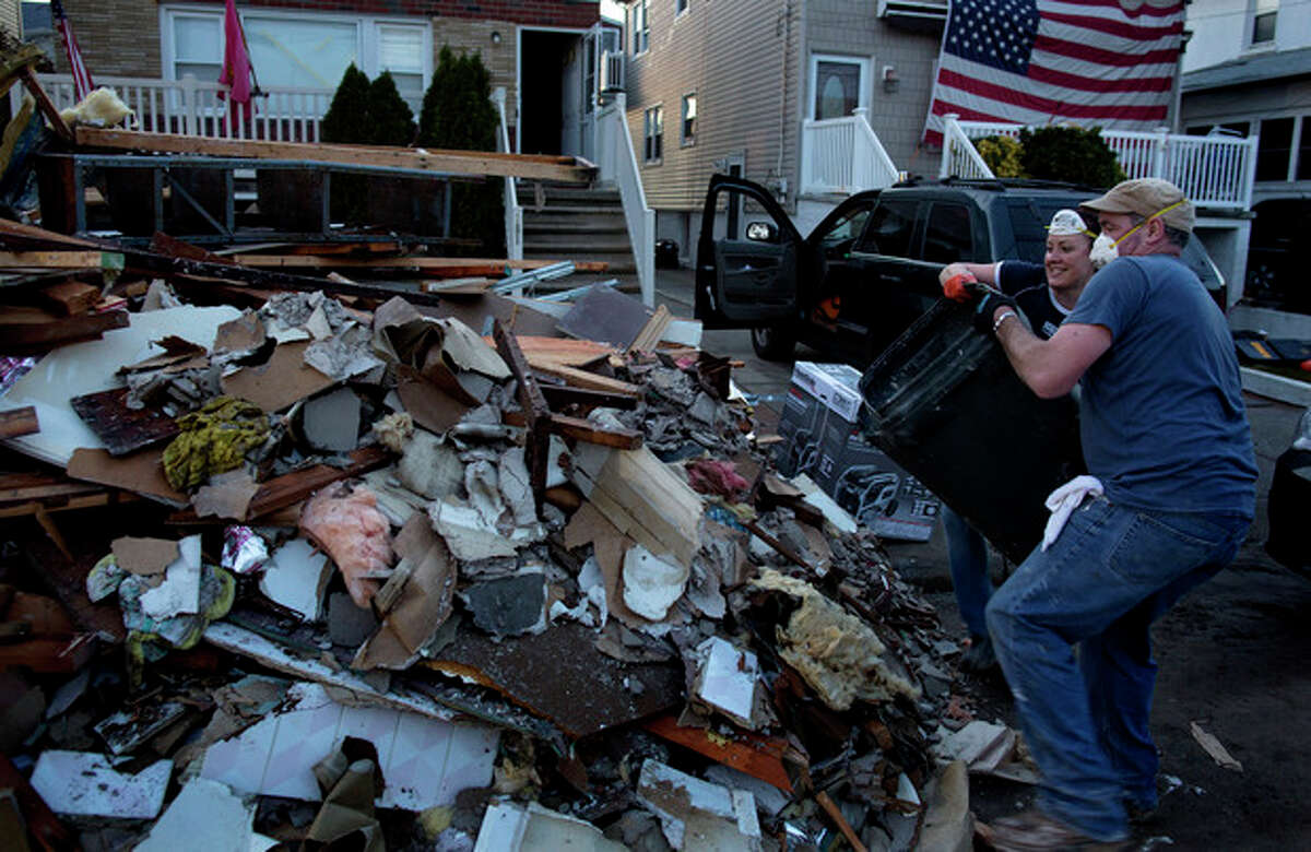 Volunteer Ashling Coleman and her husband Jerry Coleman of New York throw out the last load of debris for the day from the home of John and Ann Garvey, background left, which was damaged in the Rockaway Park neighborhood in the Queens borough of New York, Sunday, Nov. 11, 2012, from Superstorm Sandy. The Colemans, bringing other family members with them, came to the neighborhood today just to see if they could find anyone who needed help. They found the Garvey's home, offered their assistance, and were gladly welcomed in. (AP Photo/Craig Ruttle)