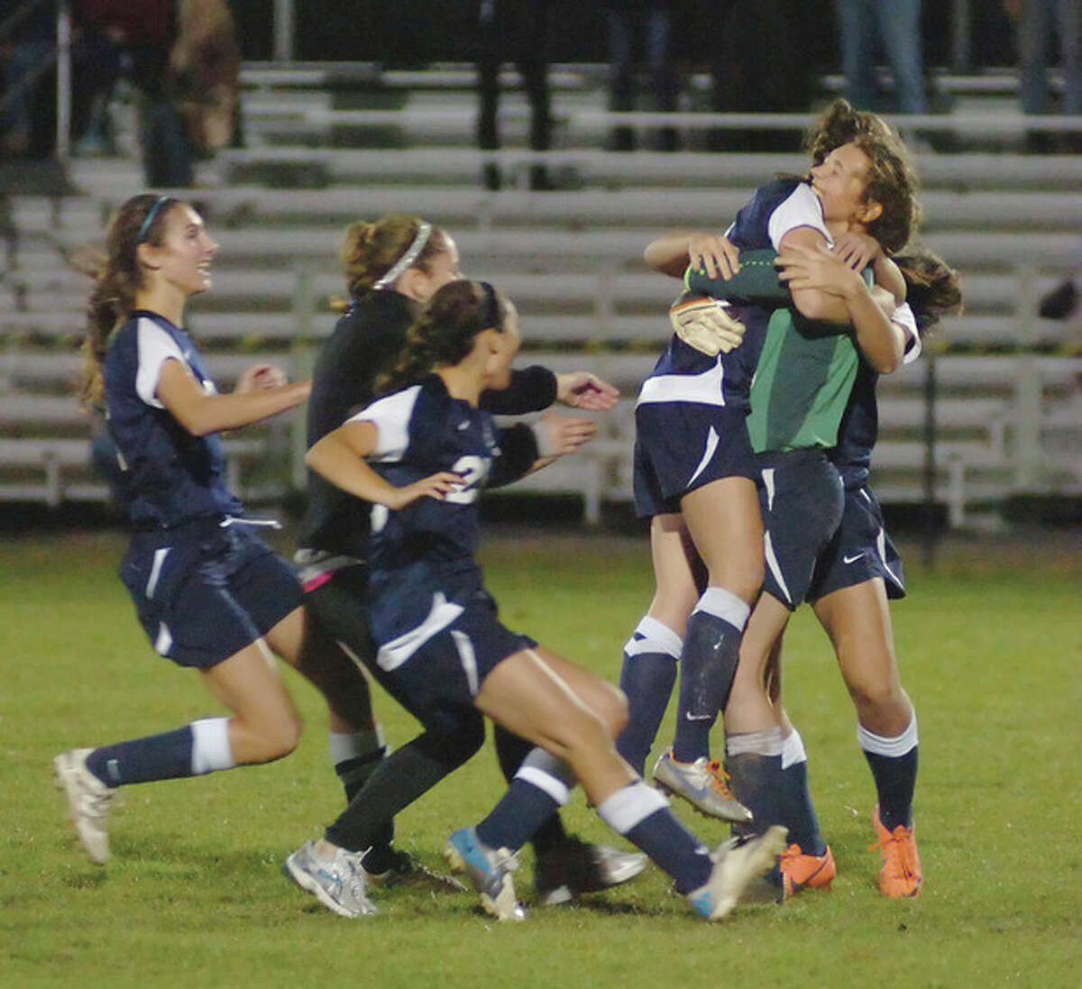 Hour photo/John Nash Wilton goalkeeper Liz Forster, right, embraces teammate Lindsay Knutson as other Warriors rush to celebrate the Warriors 4-2 advantage in penalty kicks, giving them a 2-1 win over Farmington in Monday's second round of the CIAC Class L state tournament.