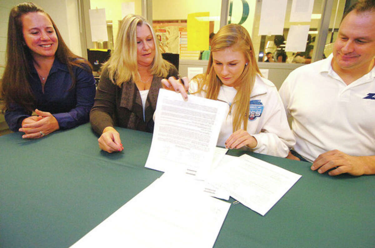 Hour photo/Alex von Kleydorff Norwalk swimmer Stephanie Czulewicz, second from right, signs her Letter of Intent to attend Central Connecticut. Watching, from left, are swim coach Rebecca Rubin, Ellie Czulewicz Don Czuliewicz.