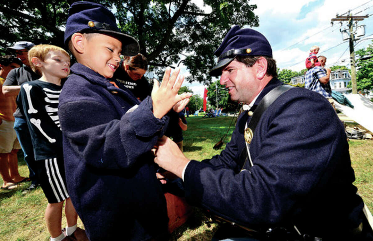 6 year old Zachary Ruiz tries on a military uniform with the help of David Fuda a reenactor with the 11th regiment of the CT Volunteer Infantry as The Norwalk Historical Society hosts the third annual Civil War BBQ and Encampment at Mill Hill Historic Park Saturday. Hour photo / Erik Trautmann