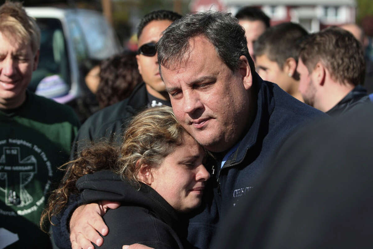 FILE - In this Nov. 3, 2012 file photo, New Jersey Gov. Chris Christie comforts Kerri Berean in Little Ferry, N.J., after Superstorm Sandy caused a tidal surge on the Hackensack River that overtook a natural berm protecting the town. For Christie, leadership after Sandy often came with an empathetic hug. For New York Gov. Andrew Cuomo, it came with an angry tirade at utilities slow to restore power. For New York City Mayor Michael Bloomberg, it came with cool, businesslike assurance. (AP Photo/The Star-Ledger, David Gard, Pool, File)
