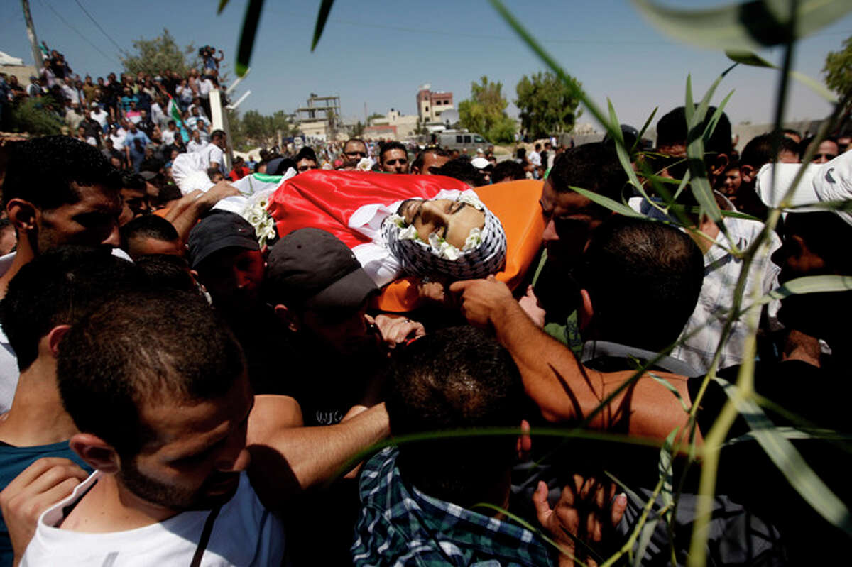 Palestinian mourners carry the body of one of three slain Palestinians, during their funeral procession in the Qalandia refugee camp, at the outskirts of the West Bank town of Ramallah, Monday, Aug. 26, 2013. Israeli soldiers killed three Palestinians in clashes during an arrest raid in the West Bank, a Palestinian official and the Israeli military said Monday, in the deadliest incident in the area in years. (AP Photo/Majdi Mohammed)