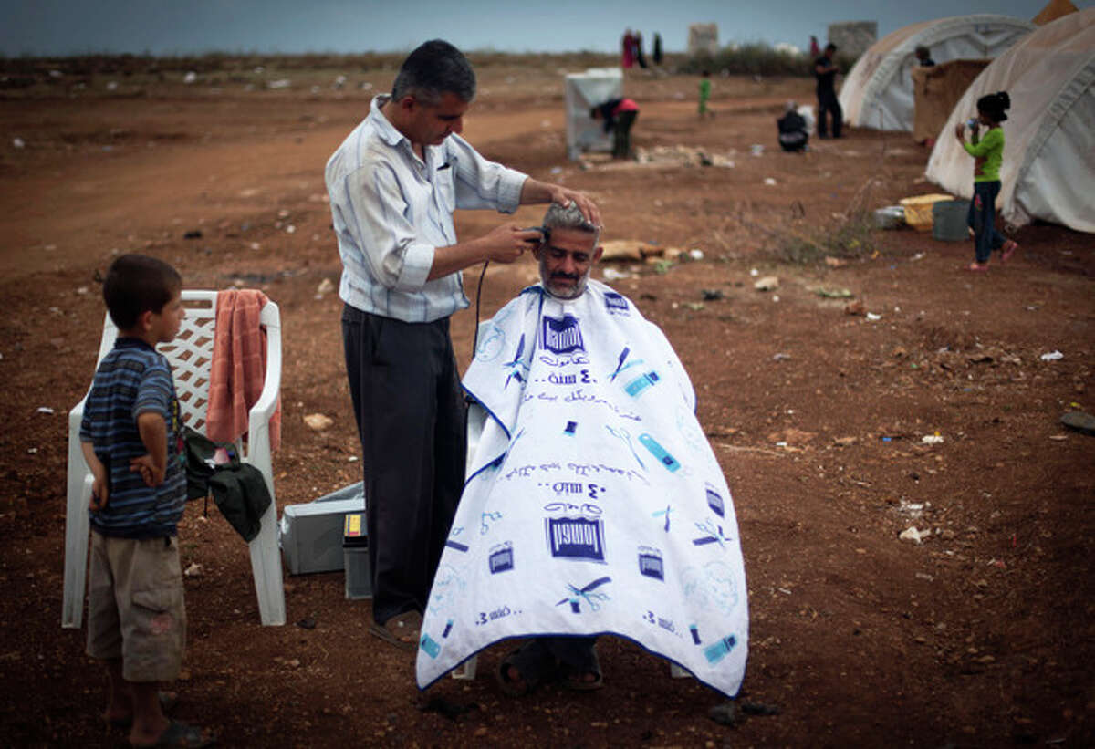 FILE - In this Thursday, Nov. 8, 2012 file photo, a Syrian man who fled from the violence in his village, sits for a haircut next to his tent at a camp, in the Syrian village of Atmeh, near the Turkish border with Syria. A dark realization is spreading across north Syria that despite 20 months of violence and recent rebel gains, an end to the war to topple President Bashar Assad is nowhere in sight. (AP Photo/Khalil Hamra, File)