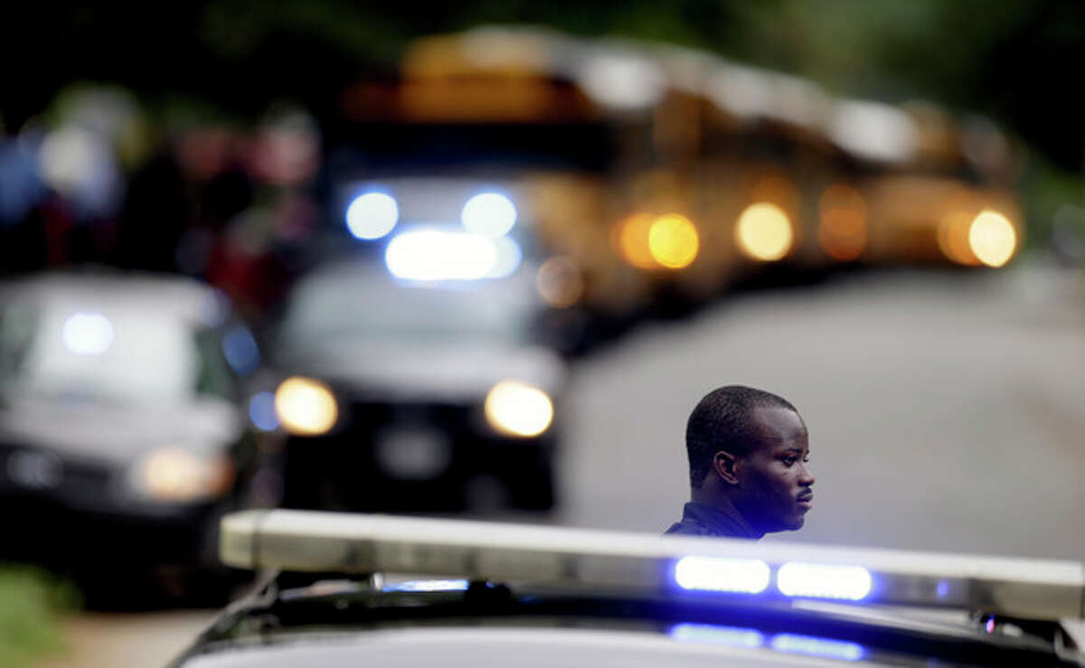 A Dekalb County Police officer stands guard as students from Ronald E. McNair Discovery Learning Academy board school buses to take them to reunite with their parents after they were evacuated after reports of a gunman entered the school, Tuesday, Aug. 20, 2013, in Decatur, Ga. All students and teachers are safe and a suspect is in custody after gunfire was heard at the Atlanta-area elementary school today. (AP Photo/David Goldman)