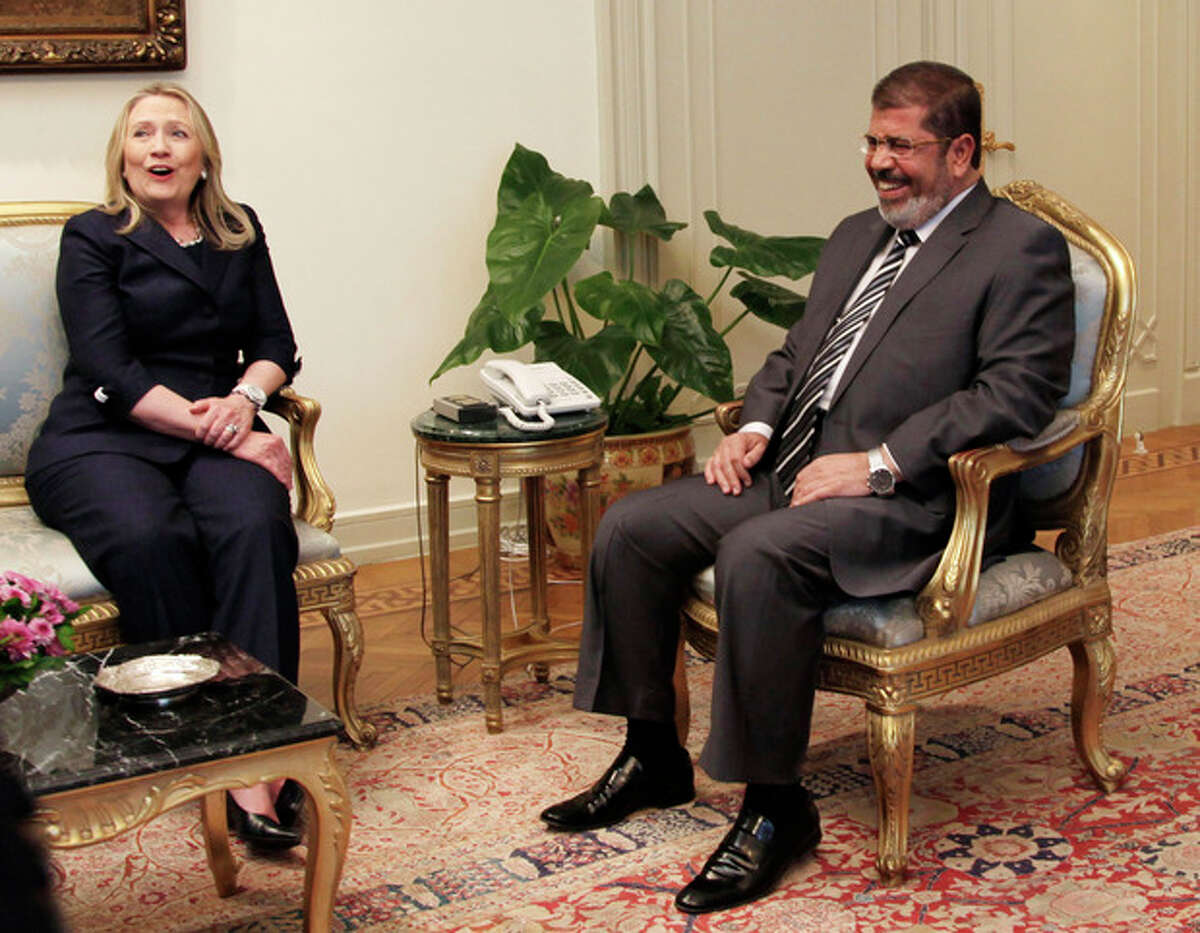 FILE - This July 14, 2012 file photo shows Secretary of State Hillary Rodham Clinton and Egyptian President Mohammed Morsi laugh during a photo opportunity at their meeting at the Presidential palace in Cairo, Egypt. The US has been here before with Egypt, praising its leader for championing Israeli-Palestinian peace efforts while expressing deep concern over his commitment to democracy at home. But with options limited, the Obama administration is keeping its faith in President Mohammed Morsi. (AP Photo/Maya Alleruzzo, File)