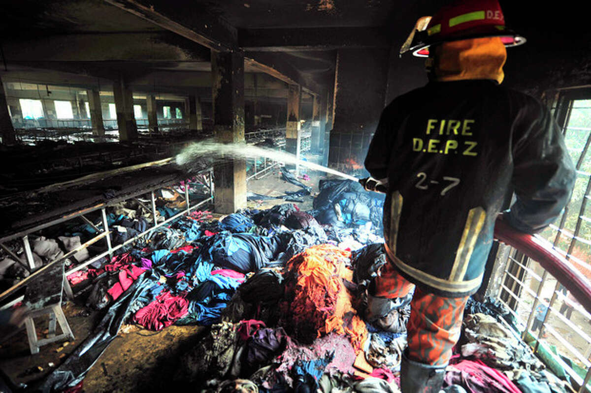 FILE - In this Sunday, Nov. 25, 2012 file photo, a firefighter douses the inside of a burned out garment factory on the outskirts of Dhaka, Bangladesh. A week after a blaze at the factory killed 112 workers, a glaring question remains unanswered: How, exactly, did brands worth fortunes end up in such a place? Retailers like Wal-Mart and Sears, whose merchandise was found in the embers, are loathe to explain. But piecing together their limited answers with records and the insight of industry experts reveals a complex and ever-morphing supply chain, in which Tazreen Fashions Ltd. was but a single, completely interchangeable link. (AP Photo/Khurshed Rinku)